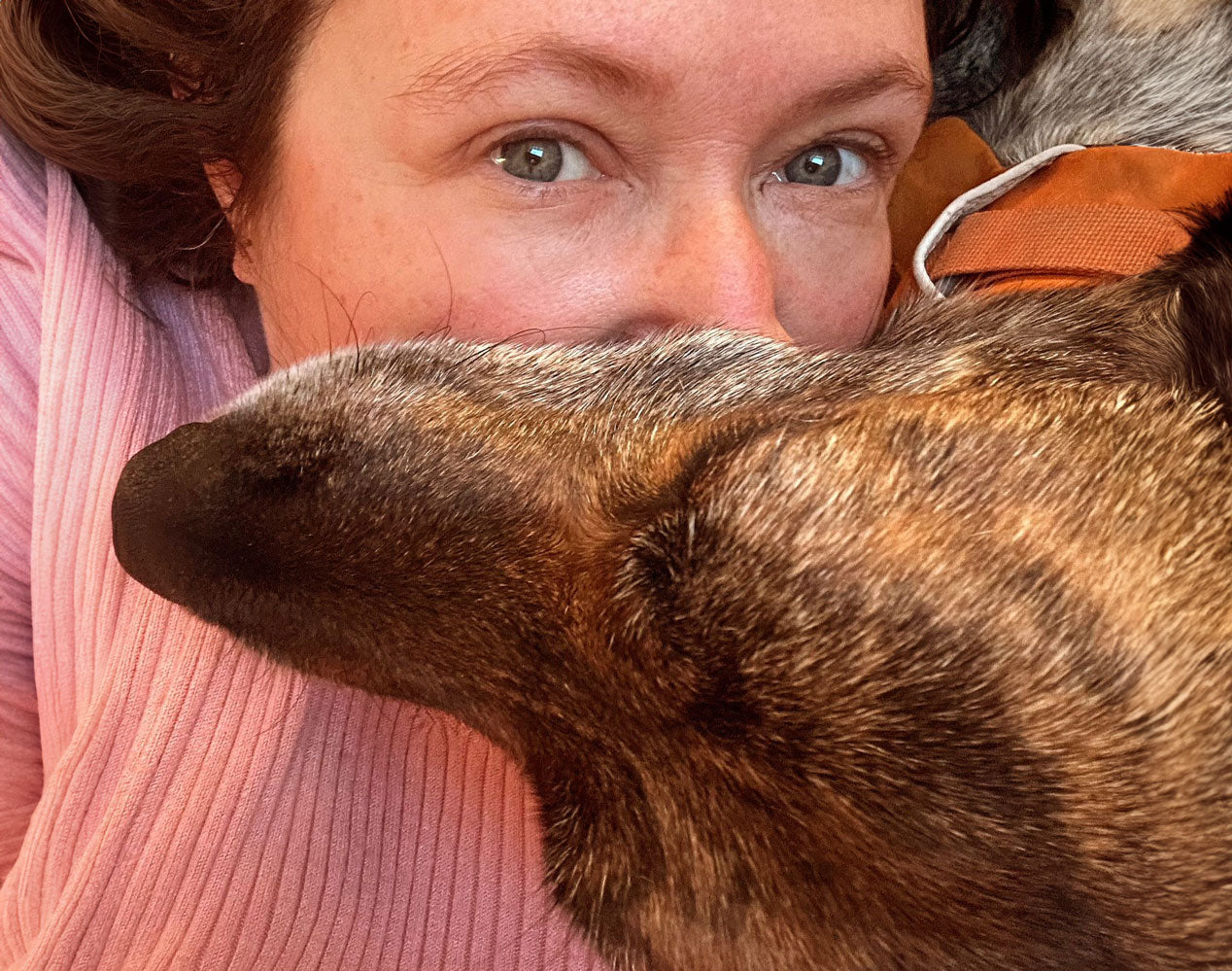 Woman with a dog lying across her upper body snuggling her